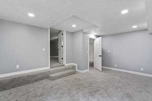 Finished below grade area featuring carpet floors, recessed lighting, baseboards, and a textured ceiling