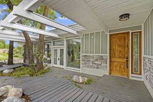 Entrance to property with board and batten siding, french doors, and stone siding