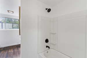Bathroom featuring tub / shower combination, wood finished floors, and baseboards