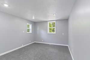 Unfurnished room featuring a textured ceiling, baseboards, dark carpet, and recessed lighting