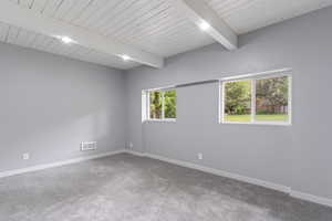 Empty room featuring baseboards, carpet floors, and wooden ceiling with exposed beams