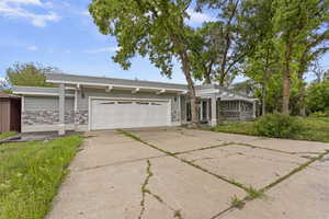 Mid-century inspired home with a garage, concrete driveway, and stone siding