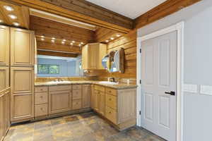 Bathroom with double vanity, wood walls, stone finish flooring, and wooden ceiling