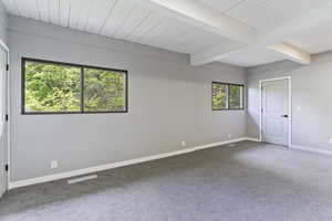 Spare room featuring carpet, baseboards, and beam ceiling
