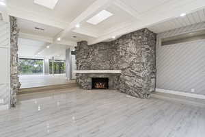Unfurnished living room featuring beamed ceiling, a fireplace, and wood finished floors