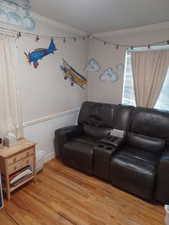 Living room with ornamental molding, light wood-style floors, and wainscoting