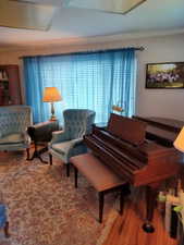 Living area with wood finished floors and ornamental molding