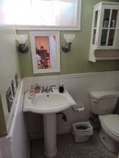 Bathroom featuring toilet, a wainscoted wall, and tile patterned floors