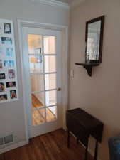 Doorway to outside featuring ornamental molding and dark wood-type flooring