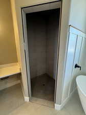 Bathroom featuring a soaking tub, a tile shower, tile patterned floors, and baseboards
