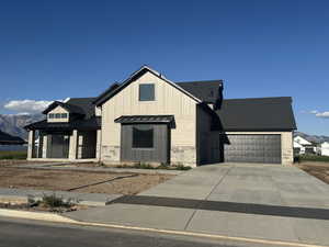 Modern farmhouse with a standing seam roof, an attached garage, metal roof, and driveway
