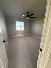 Empty room with a ceiling fan, carpet floors, and baseboards