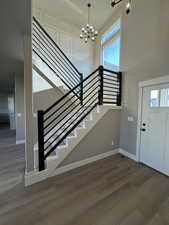 Entryway featuring a chandelier, wood finished floors, baseboards, stairway, and a towering ceiling