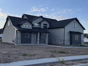 Modern inspired farmhouse with a standing seam roof, board and batten siding, a porch, metal roof, and stone siding