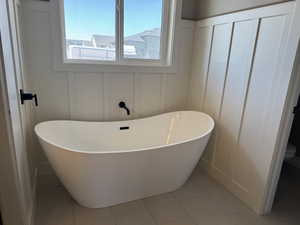 Bathroom featuring a decorative wall, a freestanding bath, tile patterned flooring, and toilet