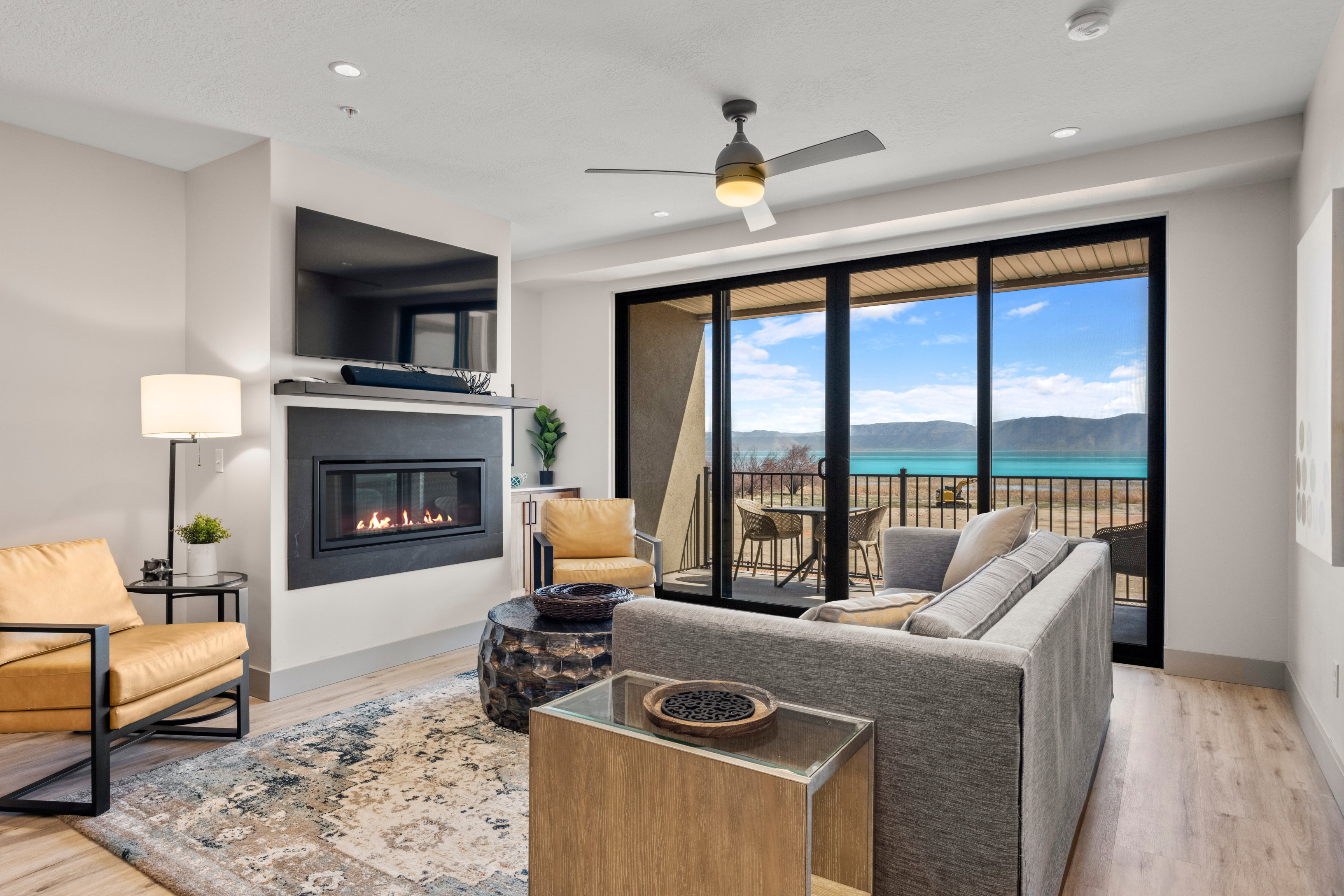 Living room with a glass covered fireplace, wood finished floors, ceiling fan, baseboards, and recessed lighting