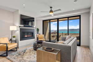 Living room with a glass covered fireplace, wood finished floors, ceiling fan, baseboards, and recessed lighting