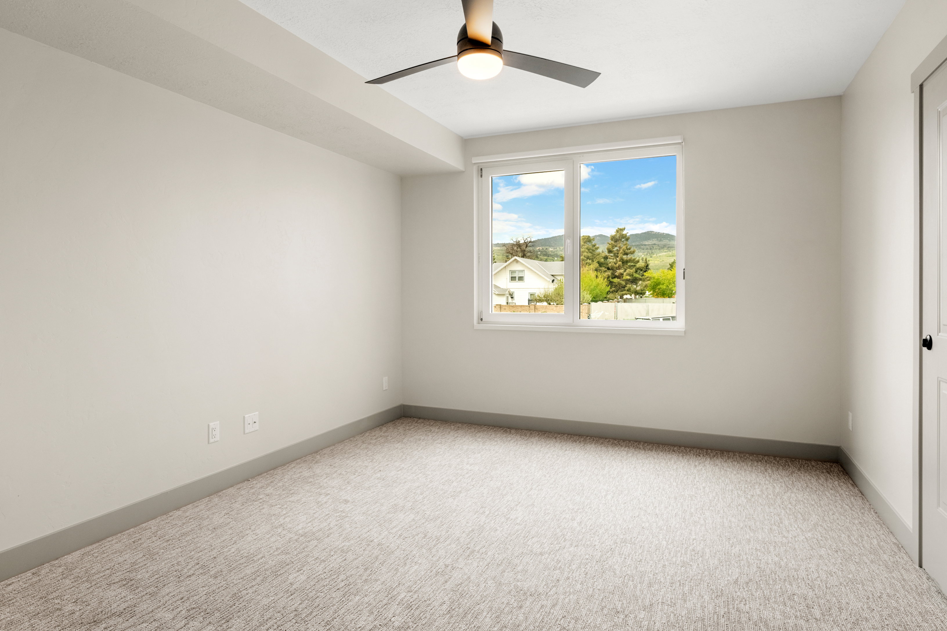 Carpeted empty room with ceiling fan and baseboards