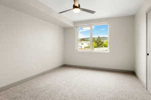 Carpeted empty room with ceiling fan and baseboards