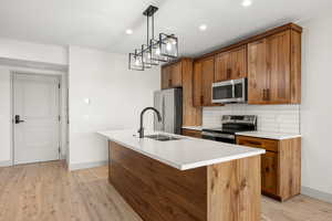Kitchen with stainless steel appliances, brown cabinets, baseboards, a sink, and recessed lighting