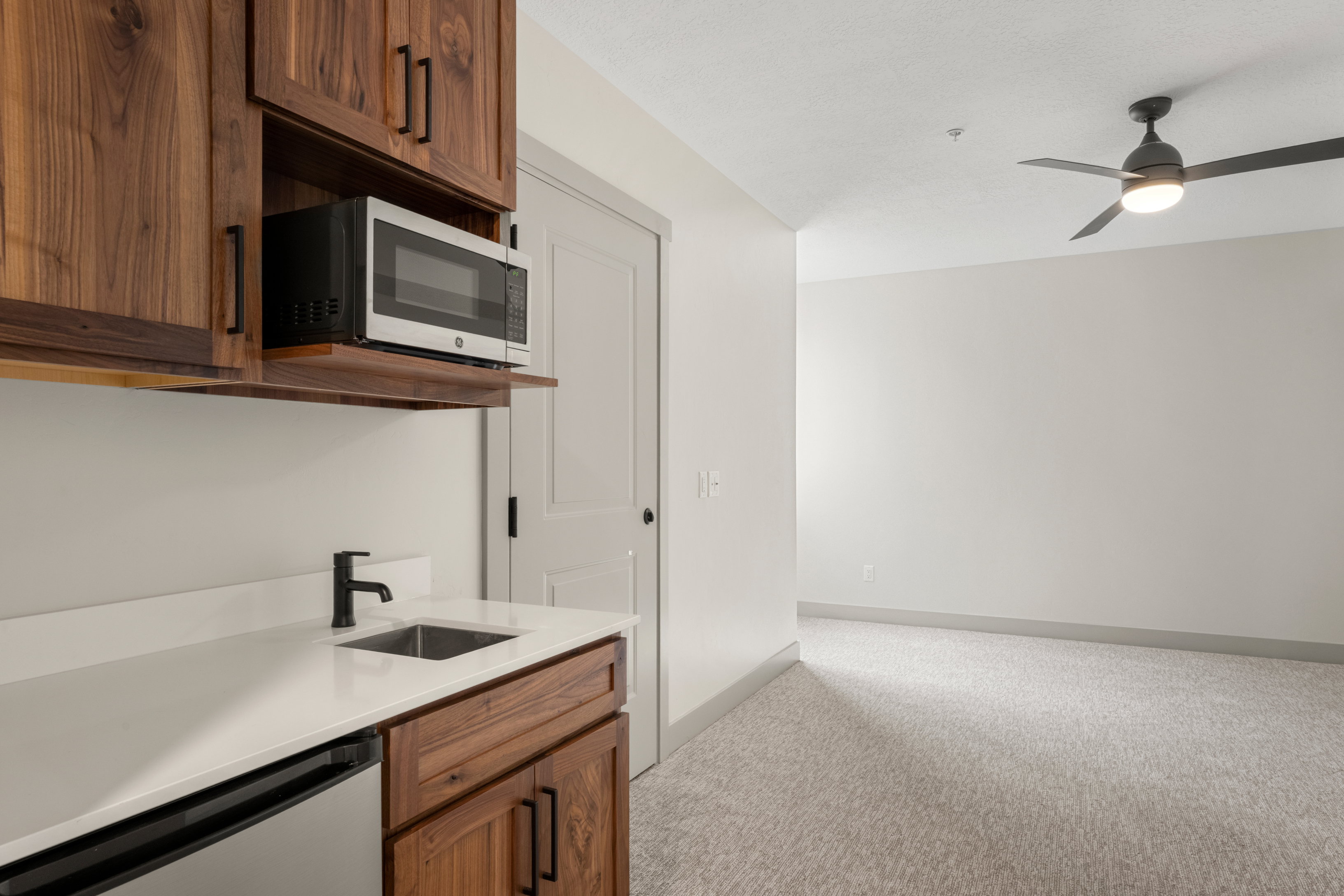 Kitchen featuring stainless steel appliances, light carpet, a sink, light countertops, and ceiling fan