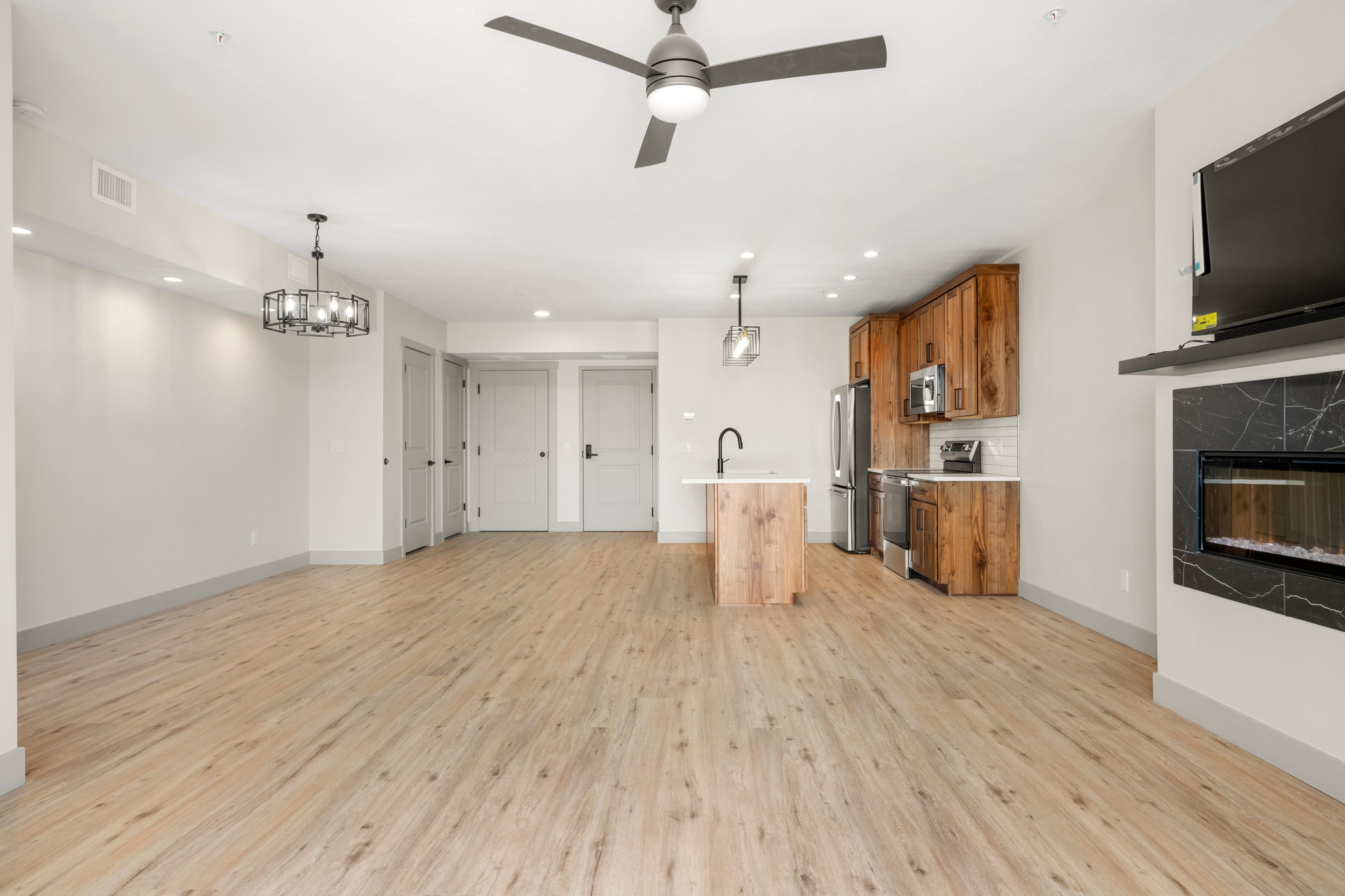 Unfurnished living room featuring light wood finished floors, ceiling fan, baseboards, a fireplace, and recessed lighting