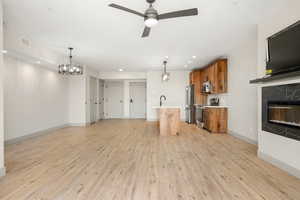Unfurnished living room featuring light wood finished floors, ceiling fan, baseboards, a fireplace, and recessed lighting