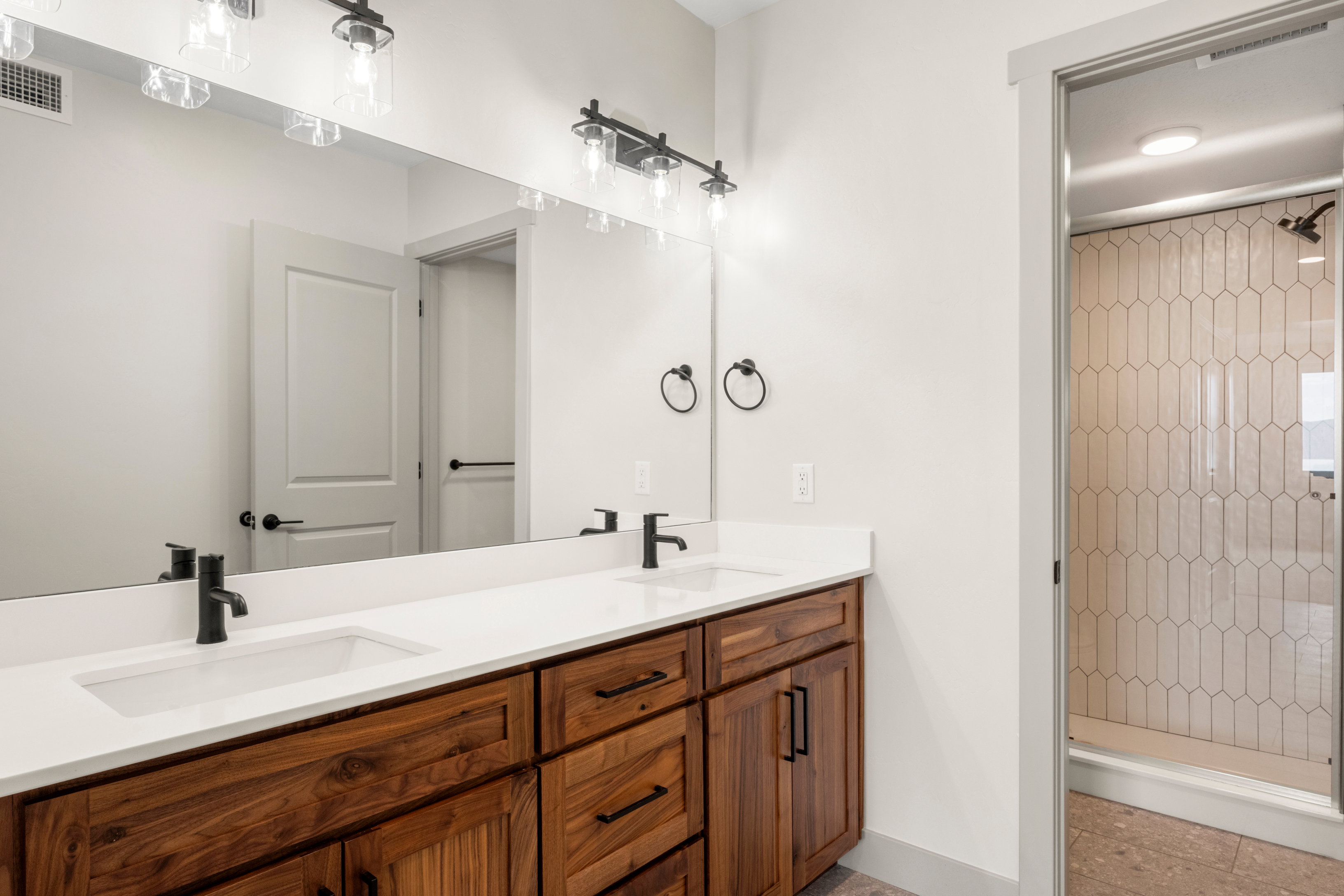 Full bath featuring a shower stall, double vanity, and baseboards