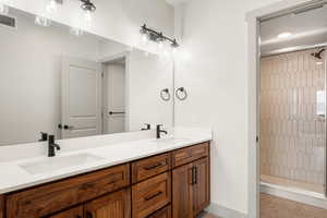 Full bath featuring a shower stall, double vanity, and baseboards