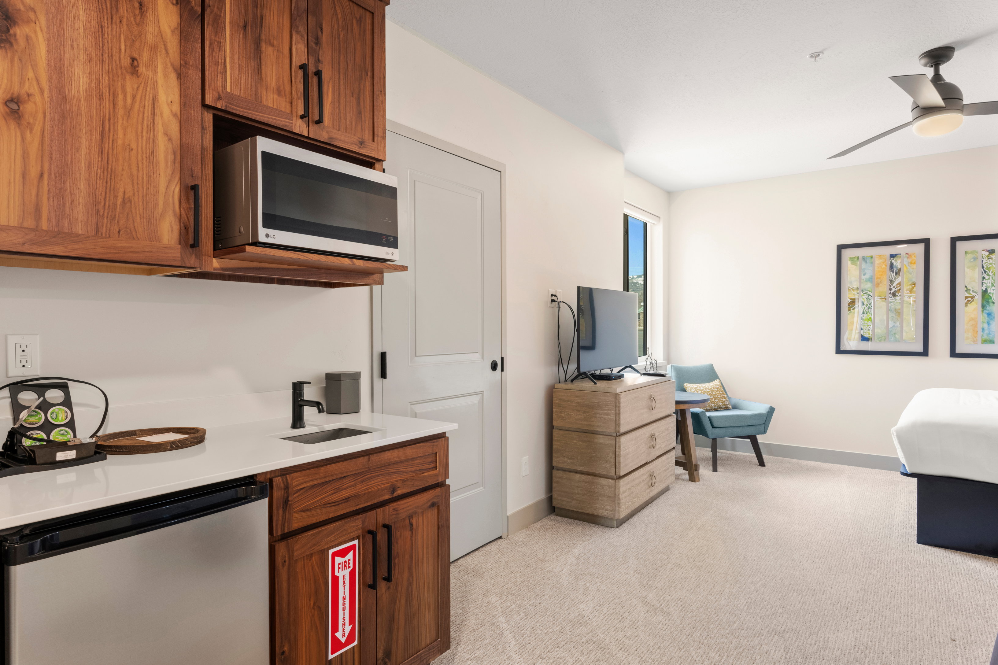 Kitchen with stainless steel appliances, light colored carpet, a sink, brown cabinetry, and baseboards