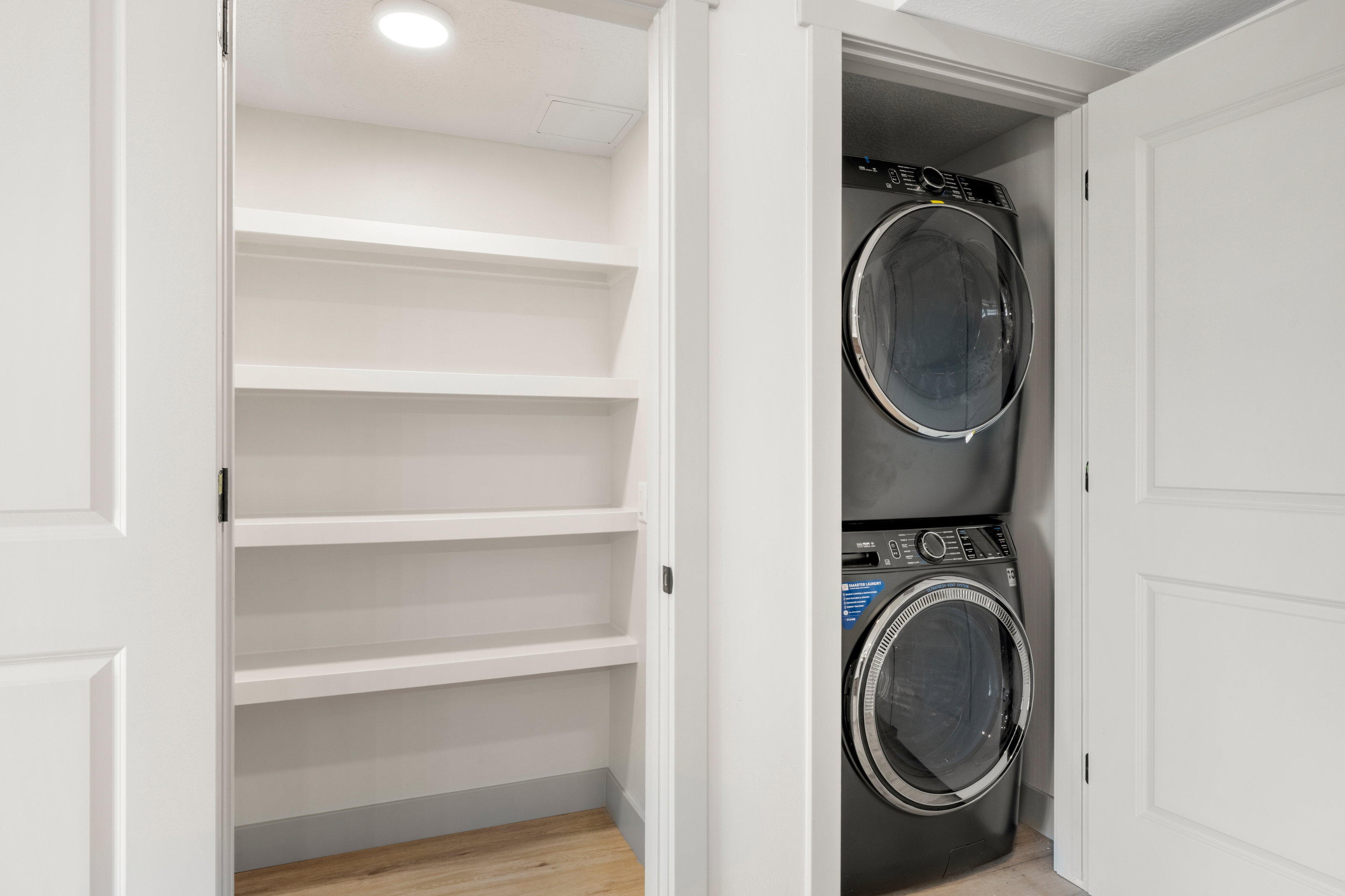 Laundry area with stacked washing machine and dryer and wood finished floors