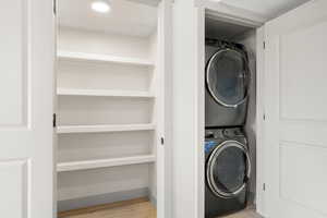 Laundry area with stacked washing machine and dryer and wood finished floors