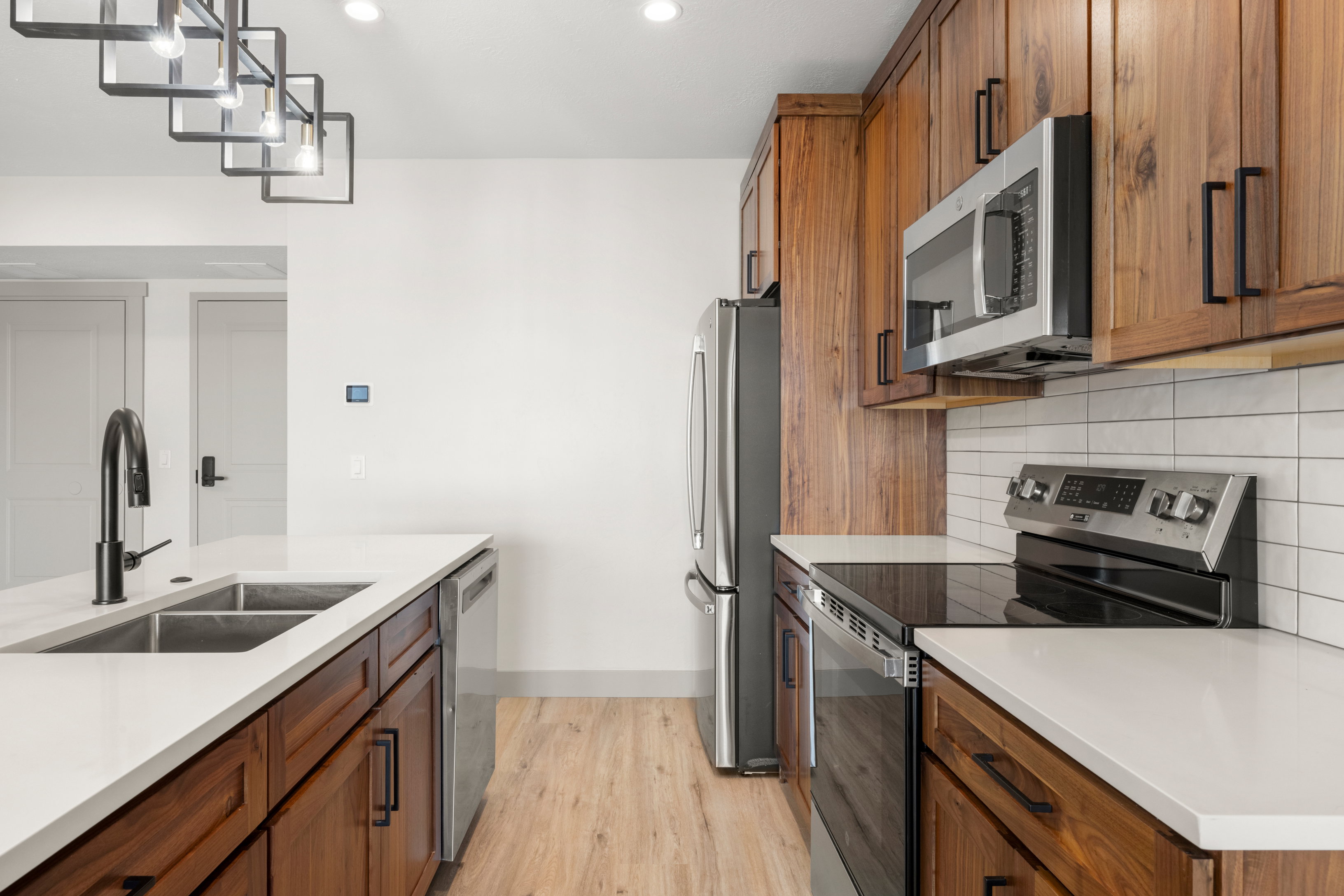 Kitchen featuring stainless steel appliances, a sink, light wood-style floors, brown cabinets, and recessed lighting