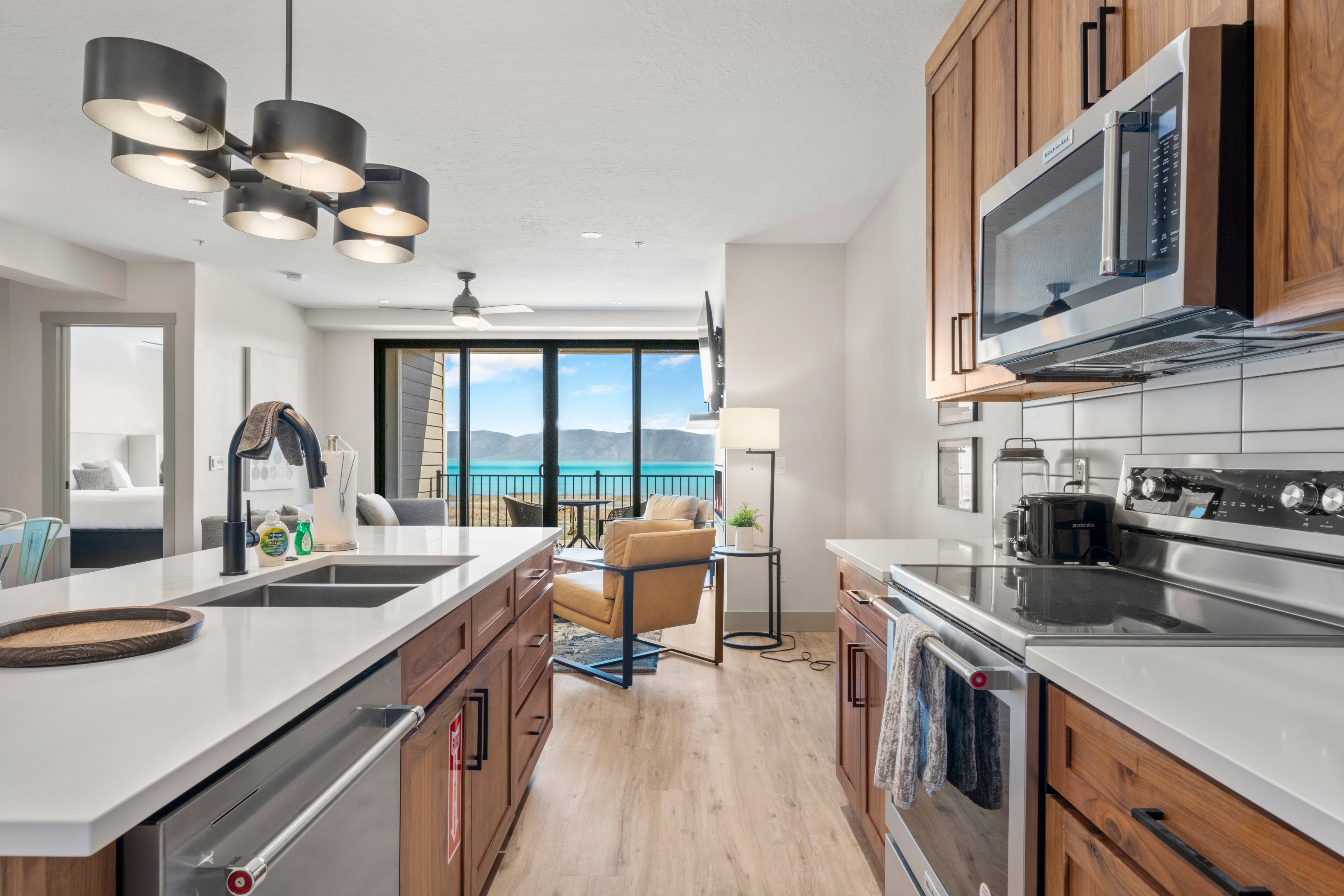 Kitchen with appliances with stainless steel finishes, a sink, brown cabinetry, open floor plan, and light wood-style floors