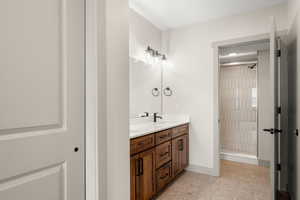 Bathroom featuring a stall shower, double vanity, baseboards, and tile patterned flooring
