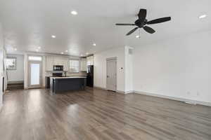Living room with healthy amount of natural light, recessed lighting, wood finished floors, baseboards, and a ceiling fan