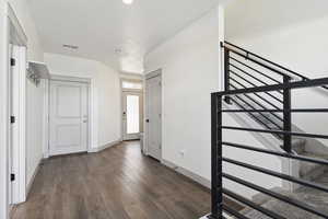 Foyer with wood finished floors, baseboards, and stairway