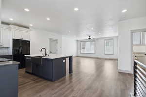 Kitchen featuring a sink, black fridge with ice dispenser, stainless steel dishwasher, wood finished floors, and recessed lighting
