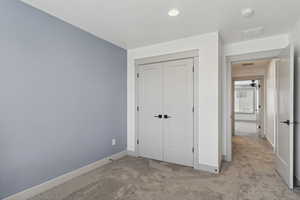 Unfurnished bedroom featuring light colored carpet, baseboards, a closet, and recessed lighting
