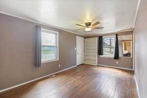 Spare room with a textured ceiling, ceiling fan, crown molding, hardwood / wood-style floors, and baseboards