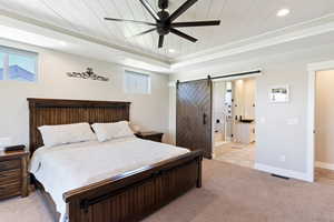 Bedroom with a barn door, light carpet, recessed lighting, wooden ceiling, and ensuite bath