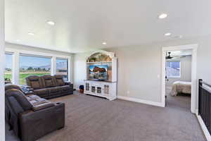 Carpeted living area with recessed lighting, baseboards, and a ceiling fan