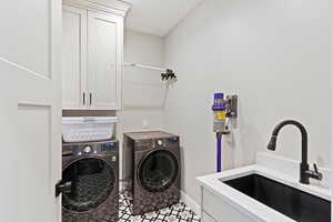 Washroom featuring cabinet space, washer and clothes dryer, and baseboards