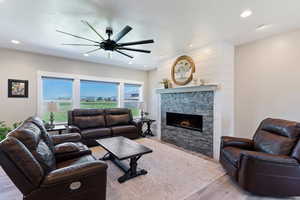 Living area featuring light wood-style floors, ceiling fan, a fireplace, and recessed lighting