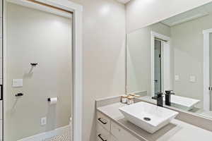 Bathroom featuring vanity, toilet, and baseboards