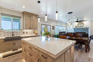 Kitchen with a sink, light wood-style floors, a fireplace, open floor plan, and tasteful backsplash