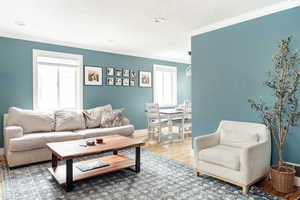 Living area featuring healthy amount of natural light, crown molding, wood finished floors, baseboards, and recessed lighting