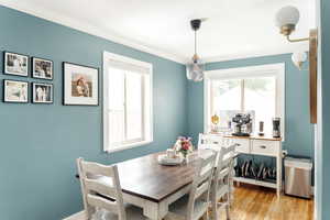 Dining room with crown molding, light wood-style floors, and baseboards