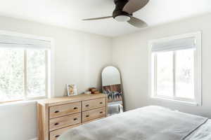Bedroom with multiple windows, ceiling fan, and baseboards