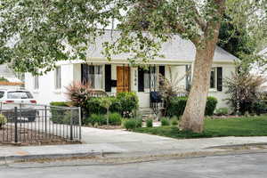 View of front of property with covered porch, a shingled roof, concrete driveway, and stucco siding